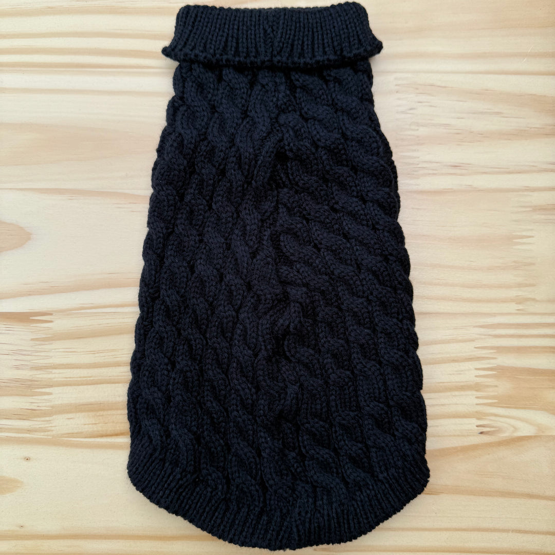 Black knitted dog sweater on a wooden surface