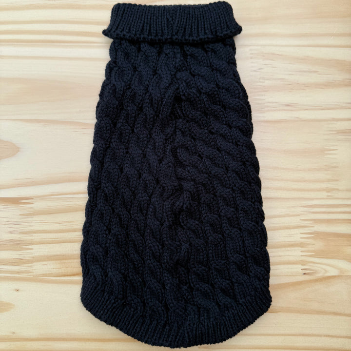 Black knitted dog sweater on a wooden surface