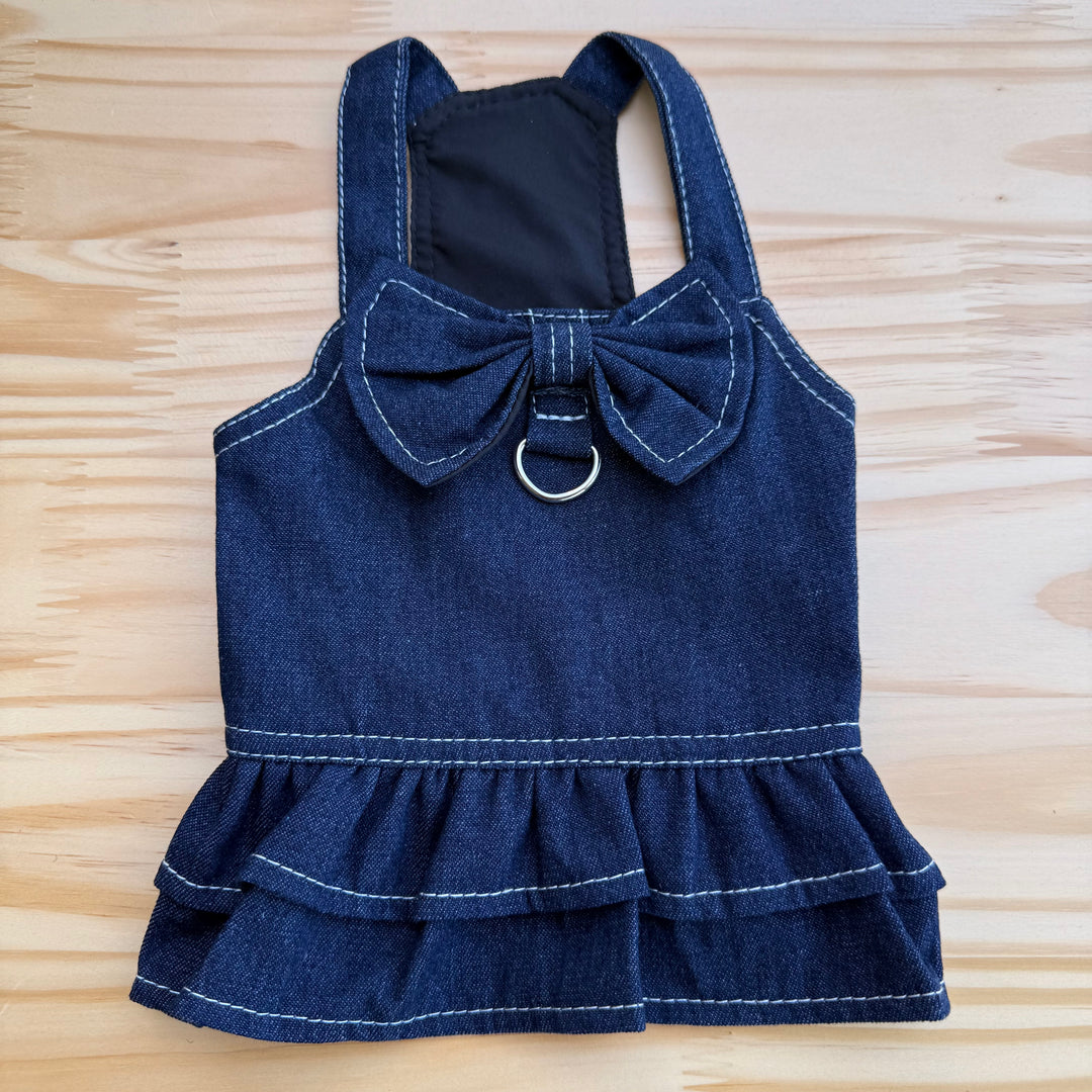 Blue denim dog dress with a bow on a wooden surface