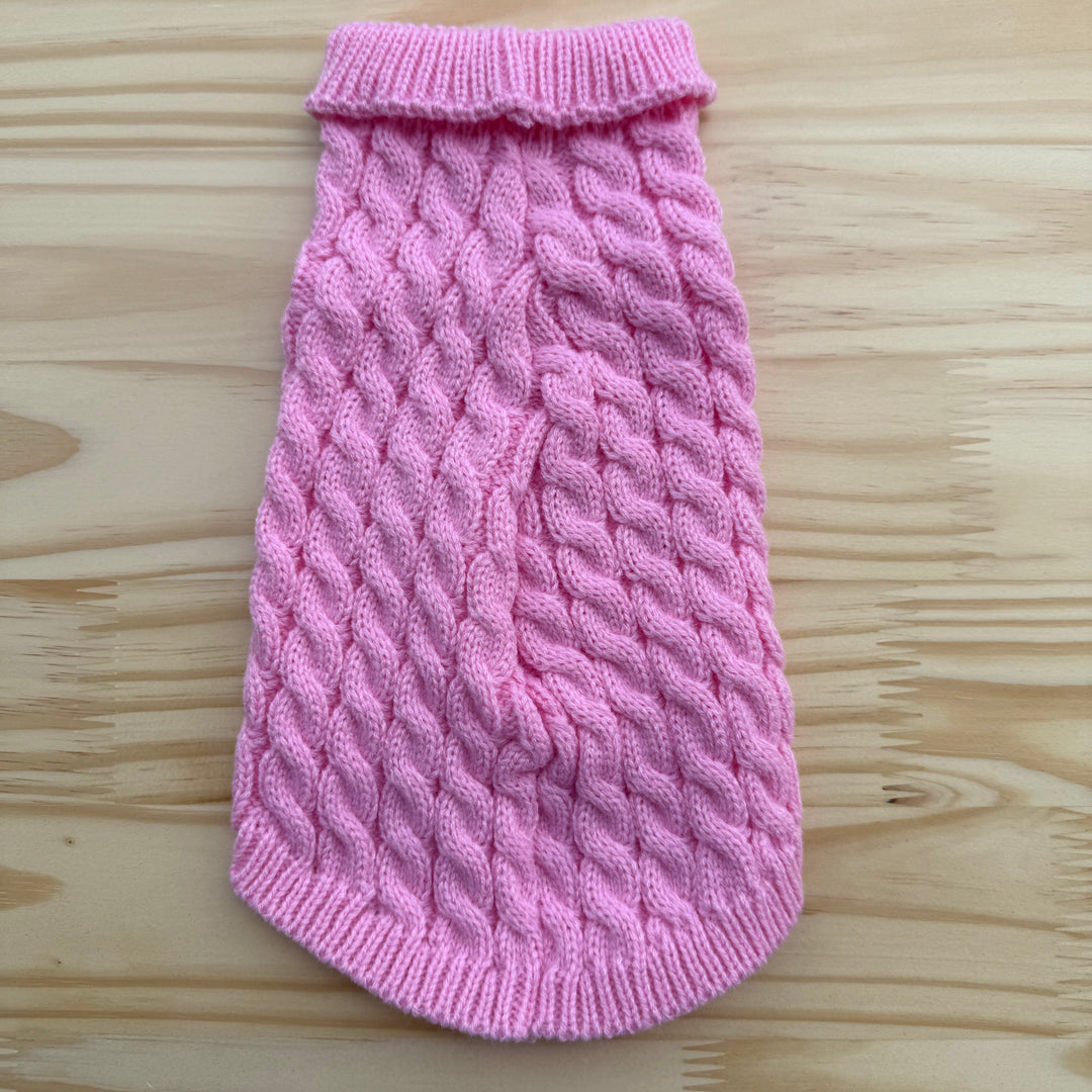 Pink knitted dog sweater on a wooden surface