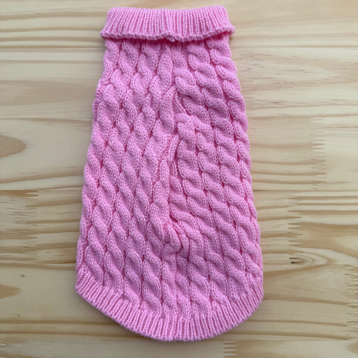 Pink knitted dog sweater on a wooden surface