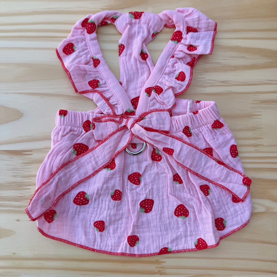 Pink dog outfit with strawberry pattern on a wooden surface