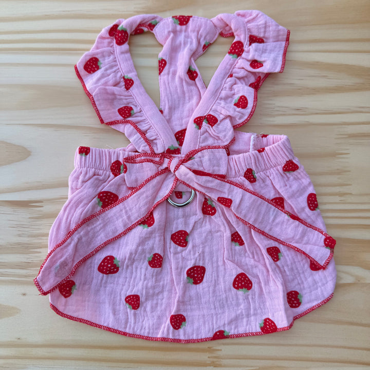 Pink dog outfit with strawberry pattern on a wooden surface
