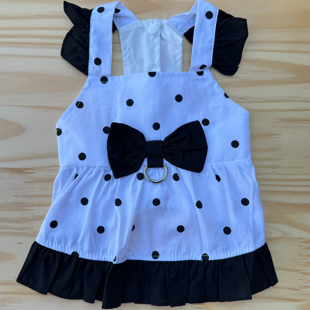 White dog dress with black polka dots and a large black bow on a wooden surface